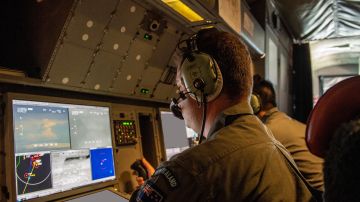 In this photo provided by the New Zealand Defense Force, a crew member from an Orion aircraft monitors equipment as it flies over an area of Tonga that has heavy ash fall from a volcanic eruption in an area of Tonga, Monday, Jan. 17, 2022. Thick ash on an airport runway was delaying aid deliveries to the Pacific island nation of Tonga, where significant damage was being reported days after a huge undersea volcanic eruption and tsunami. (CPL Vanessa Parker/NZDF via AP)