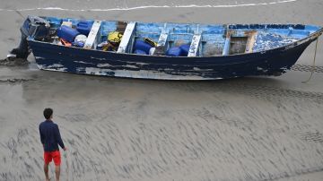 A Del Mar lifeguard looks over a capsized boat on the beach Monday, May. 5, 2025, in at Torrey Pines State beach in San Diego, Calif. (AP Photo/Denis Poroy)