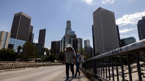 A woman wearing a sun hat crosses a bridge near downtown Los Angeles during a heatwave Friday, Sept. 6, 2024. (AP Photo/Etienne Laurent)
