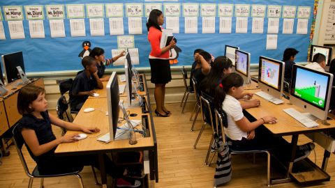In this photo taken Tuesday, May 15, 2012, Partnership for Los Angeles Coordinator of School Improvement Myeisha Phillips, middle, supervises Ritter Elementary School elementary students practicing their math operator skills in Los Angeles. As teacher layoffs result in larger class sizes, schools are increasingly looking to technology to help bear the load. Some charter schools are investing heavily in classroom computers, and Los Angeles Unified is also exploring the idea. (AP Photo/Damian Dovarganes)