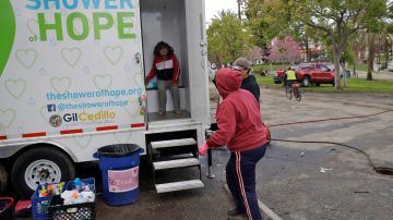 A woman enters a mobile shower as part of services for the homeless provided by The Shower of Hope MacArthur Park Monday, March 23, 2020, in Los Angeles. California residents have been told to keep away from others, not gather in groups and wash their hands frequently due to threat posed by the coronavirus. They can go out to get food, fill prescriptions, seek medical care, care for vulnerable relatives or neighbors and get exercise, such as walking.(AP Photo/Marcio Jose Sanchez)
