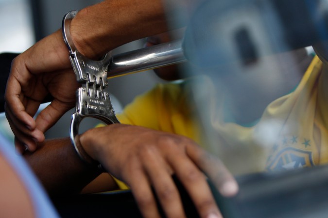 A handcuffed suspect waits inside a police bus during an operation against alleged drug traffickers at the Complexo do Alemao slum in Rio de Janeiro, Brazil, Saturday, Nov. 27, 2010. Soldiers and police crouching behind armored vehicles trained their rifles on dozens of entrances to a sprawling slum Saturday, preparing to invade and try to push drug gangs out an area long considered the most dangerous in Rio de Janeiro, a city set to host the 2016 Olympics. (AP Photo/Felipe Dana)