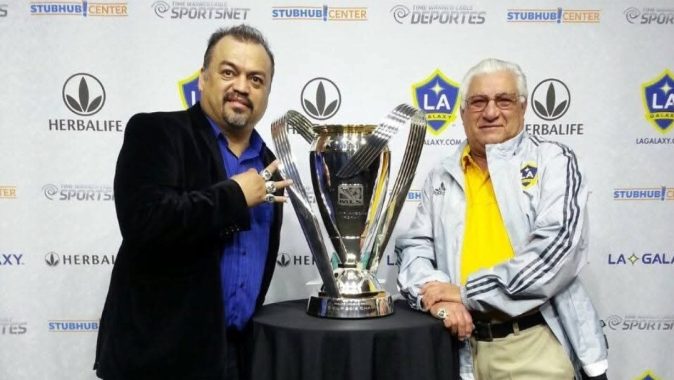 Rolando "El Veloz" González (der.) y Armando Aguayo, su compañero de transmisiones por ocho años, posan con una de las Copas MLS conquistadas por el LA Galaxy.