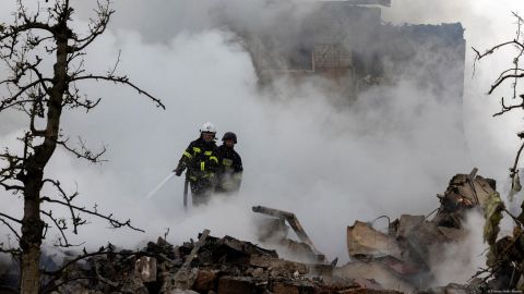 Trabajadores de los servicios de emergencia extinguen el fuego entre los escombros de una casa destruida por proyectil ruso en Kiev.
