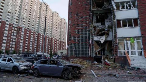 Un hombre limpia los escombros del balcón de su casa dañada por un ataque ruso con drones en Kiev, Ucrania.