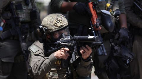 Un agente federal apunta su arma a los manifestantes durante un enfrentamiento cerca de un Home Depot después de una redada de ICE en Paramount, California.