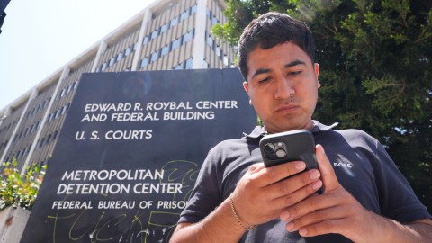 Alejandro Barranco checks his phone as he arrives to check on his father Narciso, who was detained by federal agents, outside the Metropolitan Detention Center on Monday, June 23, 2025, in Los Angeles. (AP Photo/Damian Dovarganes)
