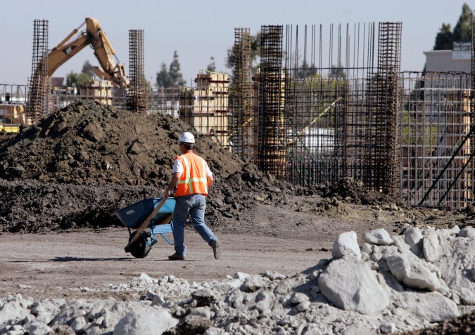 A worker pushes a wheelbarrow at an building construction project in Palo Alto, Calif., Tuesday, Oct. 23, 2007. (AP Photo/Paul Sakuma)