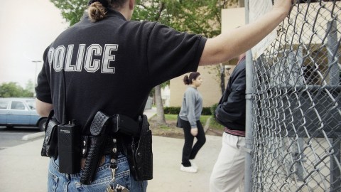 Sue Shine a Glendale Police officer stands on guard by one of the main entrances of Glendale High School as students arrive for early classes in Glendale, California on Friday, April 23, 1999. Officer Shine is posted to guard some 3400 high school students in the campus, with the aid of several campus assistants. (AP Photo/Damian Dovarganes)