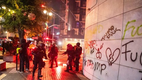 Police take cover from projectiles during protests over the Trump administration's immigration raids in Los Angeles, Monday, June 9, 2025. (AP Photo/Ethan Swope)