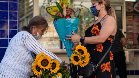 Blanca Luna, right, buys flowers from street vendor Dina Barrera in Los Angeles on Saturday, Jun. 5, 2021. Both said they had been vaccinated against COVID-19. (AP Photo/Damian Dovarganes)
