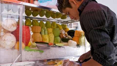 FILE - In this July 23, 2008 file photo, street vendor Antonio Tellez prepares a fruit salad at a sidewalk stand. Two members of the Los Angeles City Council want to legalize sidewalk vendors, arguing it will help people who fear deportation in the wake of President-elect Donald Trump's promise to ship out millions who are in the country illegally. Joe Buscaino and Curren Price sent a letter Tuesday, Nov. 22, 2016, to their fellow councilmembers outlining a policy to decriminalize and regulate street vending. (AP Photo/Damian Dovarganes, File)