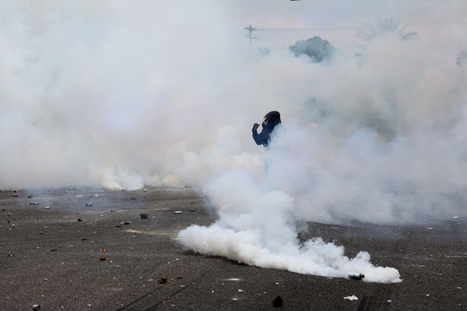 Un manifestante camina entre gases lacrimógenos disparados por agentes federales durante un enfrentamiento cerca de un Home Depot después de una redada de ICE en Paramount, California.