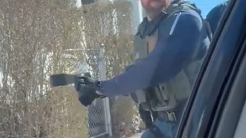 Un agente rompe el vidrio del vehículo de un migrante.
