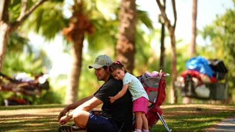 Miguel Hernandez is hugged by his one-year-old daughter Sayreli at MacArthur Park, Tuesday, July 8, 2025, in Los Angeles. (AP Photo/Damian Dovarganes)