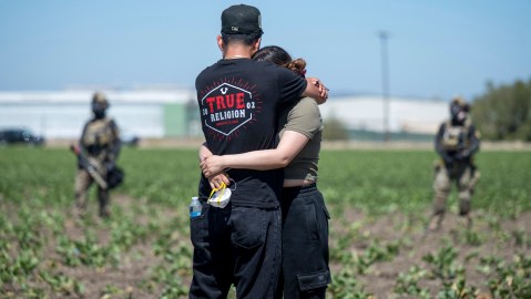 Arturo Rangel hugs Judith Ramos whose father works at the greenhouse in the background as federal immigration agents block access during a raid in the agriculture area of Camarillo, Calif., Thursday, July 10, 2025. (AP Photo/Michael Owen Baker)