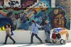 A street vendor greets an acquaintance in front the Maravilla Meat Market, with a mural depicting Cesar Chavez, left, in East Los Angeles, an area of unincorporated Los Angeles County territory east of downtown Los Angeles, Wednesday, Feb. 8, 2012. The Local Agency Formation Commission (LAFCO) voted Wednesday not to grant cityhood to East L.A., which has some 130,000 people - 96 percent of them Latino - packed into 7.4 square miles. Cityhood proponents complain that East L.A. is treated as an afterthought by the county Board of Supervisors, and they want the community to take charge of its own destiny. (AP Photo/Reed Saxon)