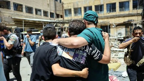 Un médico y otros hombres caminan junto a los cadáveres de los muertos en los combates en un hospital de la ciudad de Sweida.