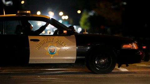 A California Highway Patrol officer sits in his car Thursday, Dec. 3, 2015, near the scene where a police shootout with suspects took place on Wednesday, in San Bernardino, Calif. A heavily armed man and woman opened fire Wednesday on a holiday banquet for his co-workers, killing multiple people and seriously wounding others in a precision assault, authorities said. Hours later, they died in the shootout with police. (AP Photo/Jae C. Hong)