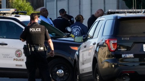 A Los Angeles Police officer and members of the Office of the Mayor of Los Angeles assist witnesses after two people were killed Tuesday, Aug. 2, 2022 in Los Angeles. Authorities say a driver who was fleeing police crashed into a homeless encampment in South Los Angeles, killing a man and a woman. (AP Photo/Damian Dovarganes)