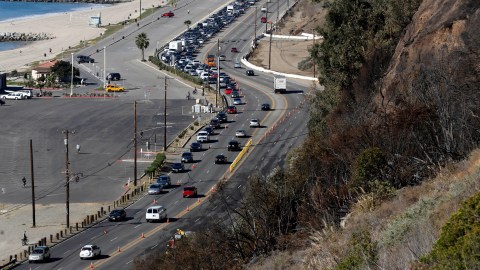 Traffic moves slowly on Pacific Coast Highway in the Pacific Palisades area of Los Angeles Wednesday, Jan. 15, 2014, after a fire threatened bluff top homes Tuesday afternoon. As Santa Ana winds made moisture plunge, plant life wither and wildfire danger soar, Southern California firefighters pounced on several small blazes before they could surge, though another day of dryness awaited. (AP Photo/Reed Saxon)