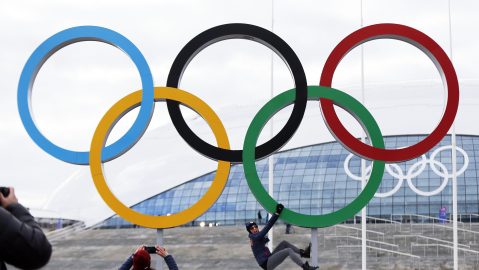 FILE - A participant hangs from the Olympic rings while posing for a teammate at Olympic Park ahead of the 2014 Winter Olympics, Wednesday, Feb. 5, 2014, in Sochi, Russia. A commission charged with reviewing the Olympic system in the United States recommended in a report Friday, March 1, 2024, that Congress rework key facets of the U.S. Center for SafeSport, including making it completely independent of the U.S. Olympic and Paralympic Committee and reimagining the way it deals with cases in the grassroots. (AP Photo/Robert F. Bukaty, File)