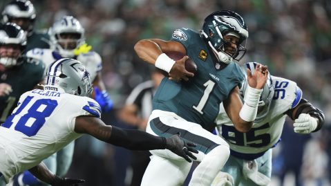 Jalen Hurts, quarterback estrella de los Eagles, corre con el balón ante la acometida de Damone Clark (18) y Kenny Clark (95), de los Cowboys, durante el partido inaugural de la temporada 2025.