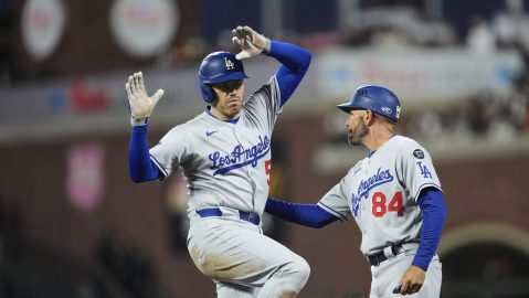 Los Angeles Dodgers' Freddie Freeman, left, celebrates with first base coach Chris Woodward after hitting a single during the fifth inning of a baseball game against the San Francisco Giants, Saturday, Sept. 13, 2025, in San Francisco. (AP Photo/Godofredo A. Vásquez)