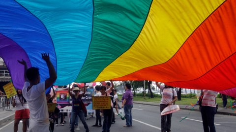 Participants raise a giant gay pride flag during the annual Pride March in Manila, Philippines, Saturday, Dec. 3, 2011. Lesbians, gays, bisexual and transgenders called for the urgent need to pass the anti-discrimination bill and for government protection from hate crimes committed against them. (AP Photo/Pat Roque)