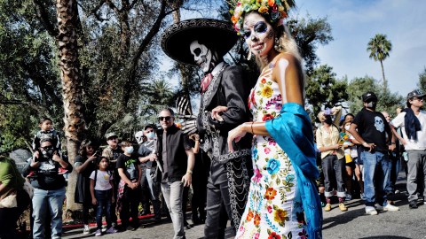 Dressed in traditional make-up and costume a couple participates in a procession during the celebration for the Day of the Dead at the Hollywood Forever Cemetery in Los Angeles on Saturday, Oct, 30, 2021. Day of the Dead, is a Mexican holiday where families welcome back the souls of their deceased relatives for a brief reunion that includes food, drink and celebration. (AP Photo/Richard Vogel)