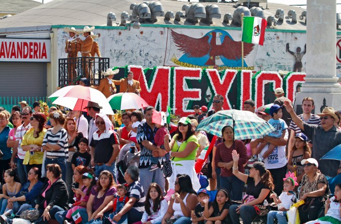 Spectators watch floats pass along the street, during the East L.A. Mexican Bicentennial Independence Day Parade, in Los Angeles on Sunday, Sept. 12, 2010. (AP Photo/Richard Vogel)