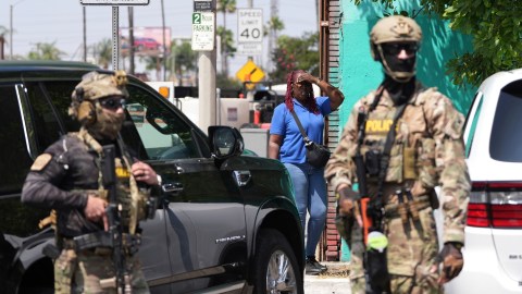 A bystander watches as immigration agents conduct an operation at a car wash on Friday, Aug. 15, 2025, in Montebello, Calif. (AP Photo/Gregory Bull)