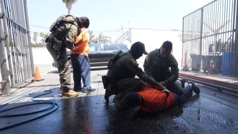 Immigration agents detain two men at a car wash on Friday, Aug. 15, 2025, in Montebello, Calif. (AP Photo/Gregory Bull)