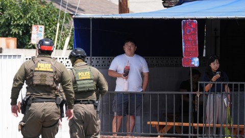 People watch as immigration agents conduct an operation at a car wash on Friday, Aug. 15, 2025, in Montebello, Calif. (AP Photo/Gregory Bull)