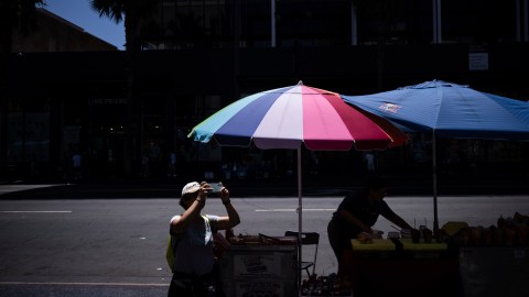 A visitor takes pictures of the TCL Chinese Theatre as a street vendor works nearby in the Hollywood section of Los Angeles, Tuesday, Aug. 19, 2025. (AP Photo/Jae C. Hong)