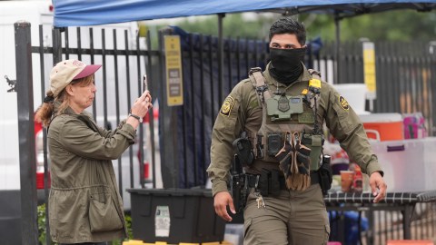 A U.S. Customs and Border Protection agent is filmed during an operation outside a Home Depot Friday, Aug. 15, 2025, in Los Angeles. (AP Photo/Gregory Bull)