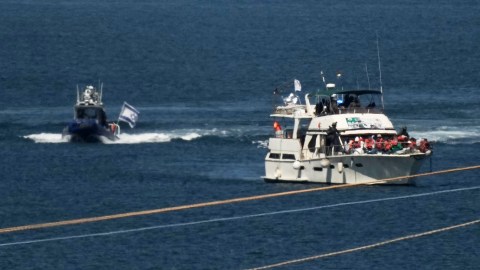 Activists in orange life jackets sit aboard a Gaza-bound Sumud flotilla boat as Israeli navy soldiers sail it into the port of Ashdod, Israel, Thursday, Oct. 2, 2025, after it was intercepted while approaching the Gaza coast. (AP Photo/Leo Correa)