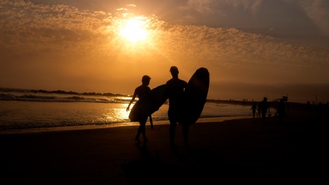 Surfers are silhouetted as they leave the water during the sun set on Wednesday, June 16, 2021, in the Venice Beach section of Los Angeles. An unusually early and long-lasting heat wave brought more triple-digit temperatures Wednesday to a large swath of the U.S. West, raising concerns that such extreme weather could become the new normal amid a decades-long drought.(AP Photo/Ringo H.W. Chiu)