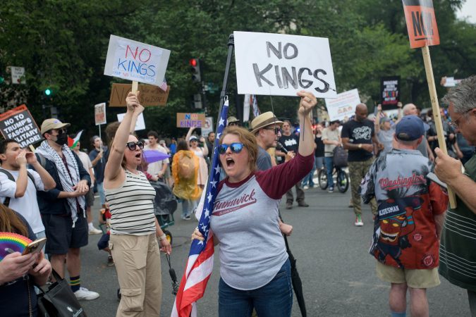People hold signs reading, "NO KINGS," during a protest taking place on the day of a military parade commemorating the Army's 250th anniversary, coinciding with President Donald Trump's 79th birthday, Saturday, June 14, 2025, in Washington. (AP Photo/Rod Lamkey, Jr.)