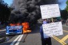A protester is seen as a Waymo taxi burns near the metropolitan detention center of downtown Los Angeles, Sunday, June 8, 2025, following last night's immigration raid protest. (AP Photo/Jae C. Hong)