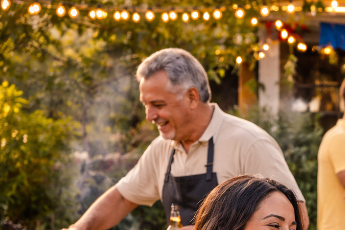 Familia y amigos latinos celebrando al aire libre con comida, música y abrazos