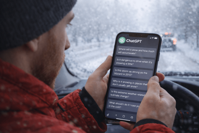 Consultas sobre nieve en ChatGPT desde el auto en plena tormenta Hombre usando ChatGPT en su celular dentro de un auto durante una tormenta de nieve en Estados Unidos