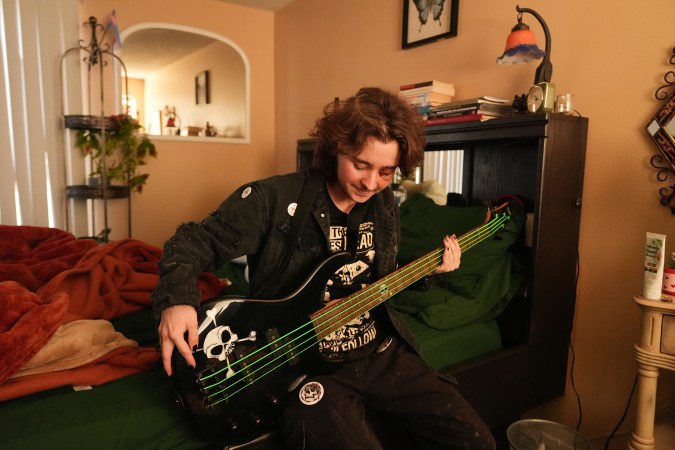 Kaden Rummler, who was injured after being hit with a projectile fired by a federal agent during a protest outside an immigration building in Santa Ana, Calif., plays the bass at home Wednesday, Jan. 14, 2026, in Southern California. (AP Photo/Damian Dovarganes)