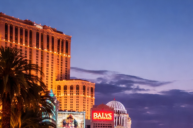 Las Vegas Strip al atardecer con hoteles iluminados y tráfico en la avenida principal