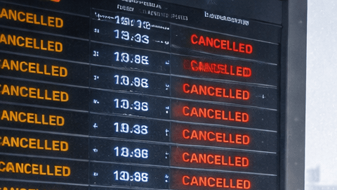 Pasajeros esperan en un aeropuerto mientras vuelos son cancelados por una tormenta invernal y aviones permanecen en tierra cubiertos de nieve.