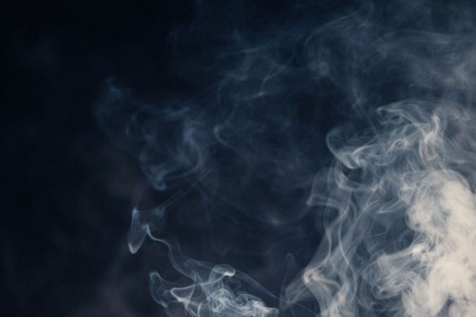 Joven adulto inhalando marihuana, con humo visible y posible impacto en la salud pulmonar y cerebral.