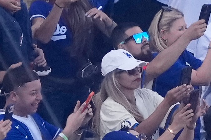 Miguel Rojas y Freddie Freeman cargan los trofeos de las pasadas dos Series Mundiales de los Dodgers mientras son transportados en un auto por el actor Will Ferrell en la ceremonia de apertura de la temporada 2026.