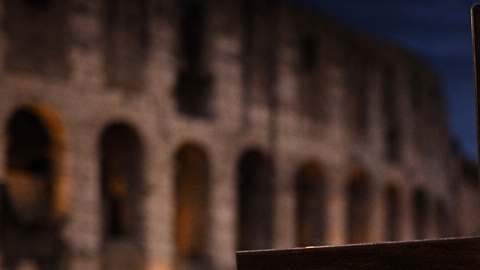 Papa de espaldas cargando una cruz durante el Vía Crucis frente al Coliseo de Roma en Viernes Santo