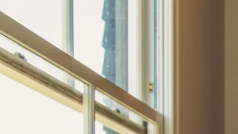 Brian Chesky, CEO de Airbnb, sentado en un sofá en una sala con paredes de madera, fotografía oficial corporativa.