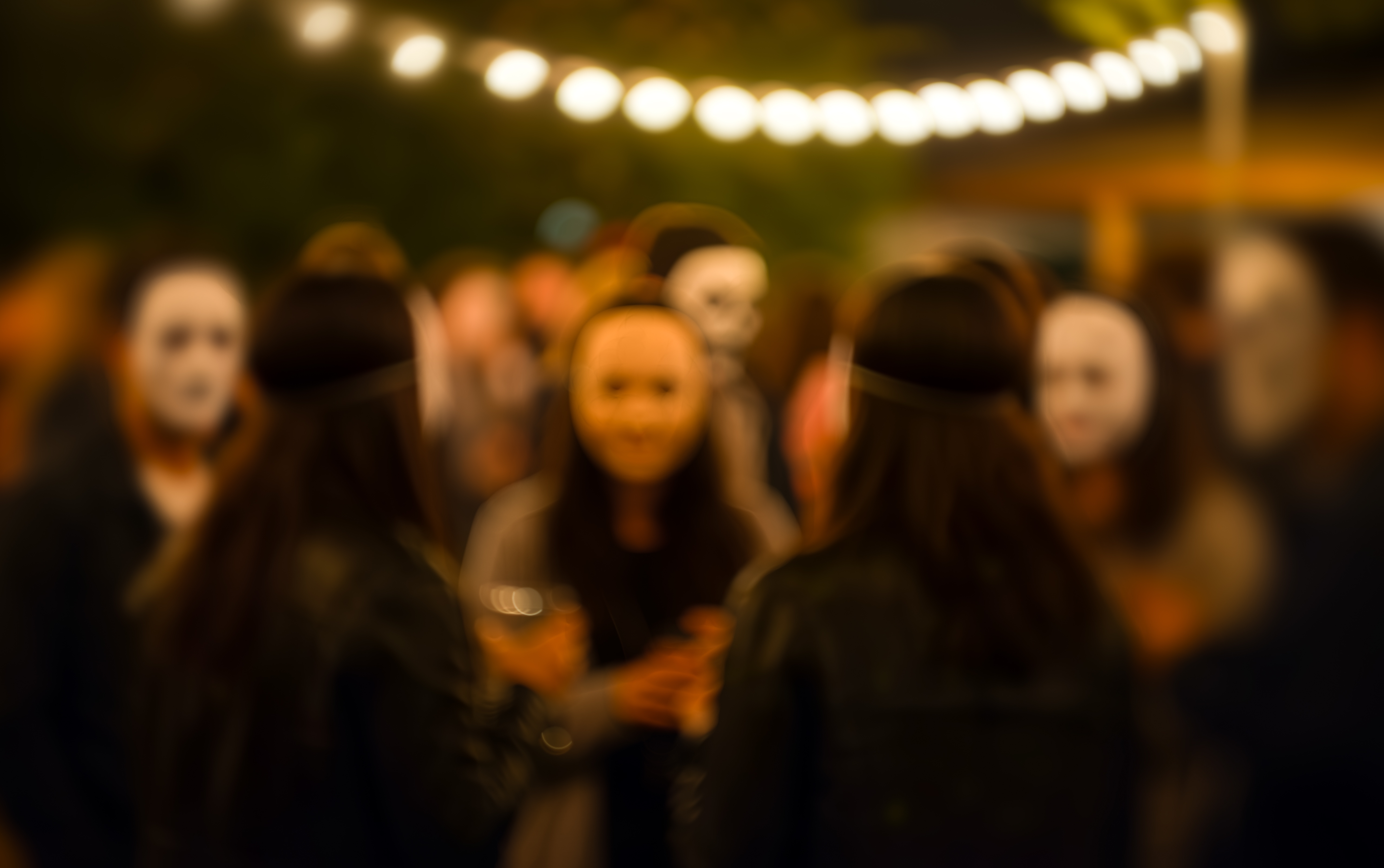 People,Wearing,White,Masks,Gather,Outdoors,Under,String,Lights,Dark